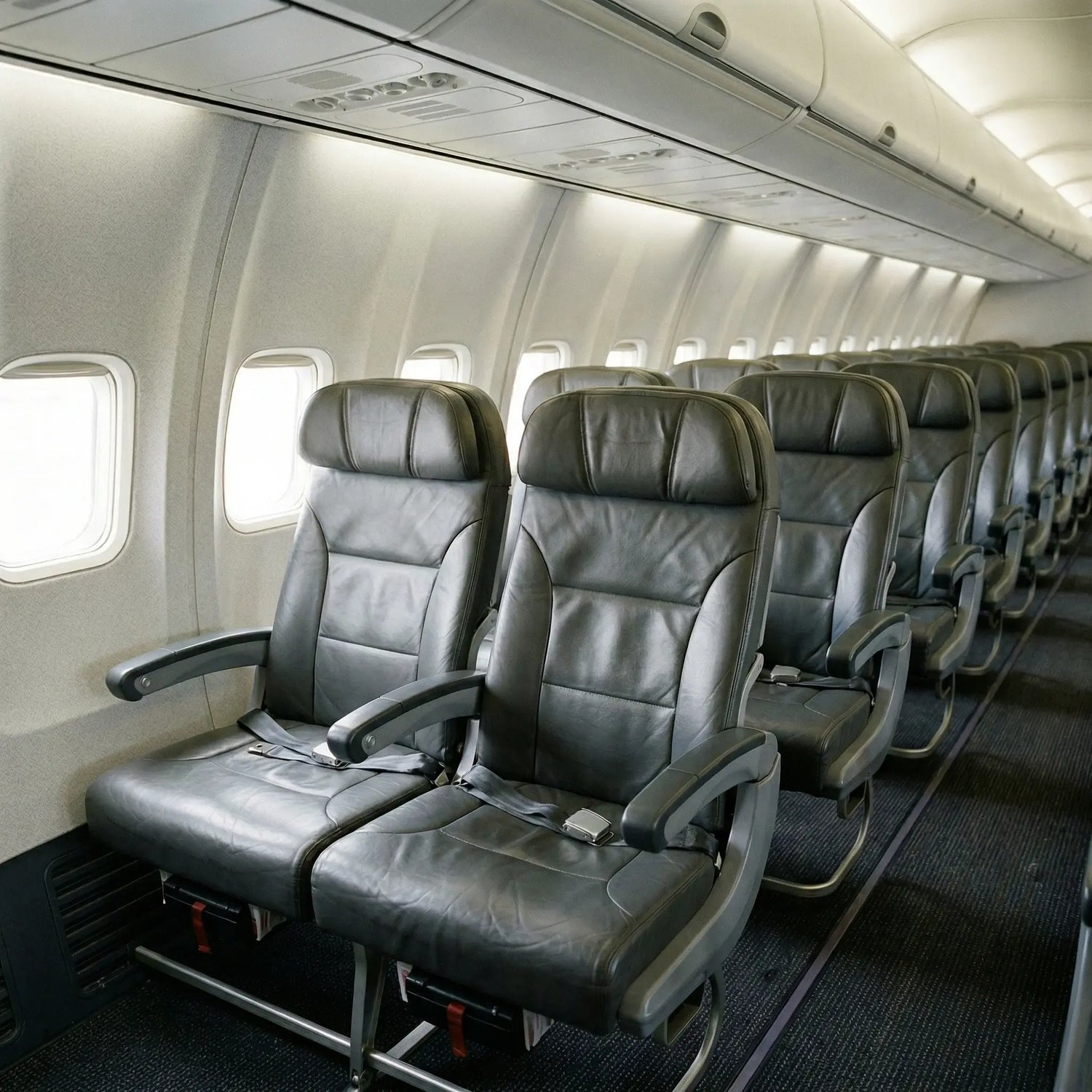 Row of black airplane seats in an aircraft cabin. Leather restoration for airplanes by Letech