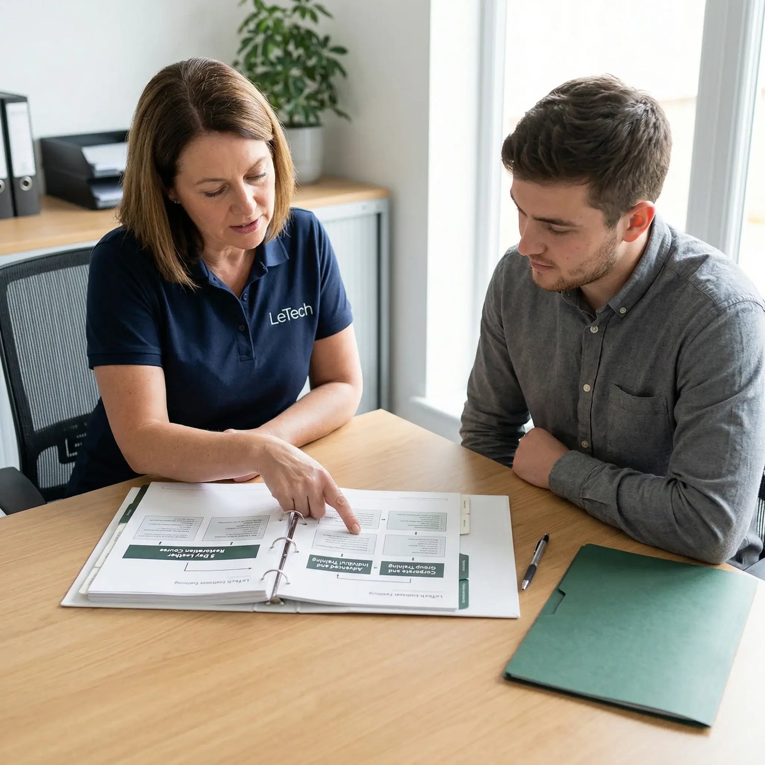 Two people reviewing a document together at a desk in an office setting. Advanced leather restoration courses by letech