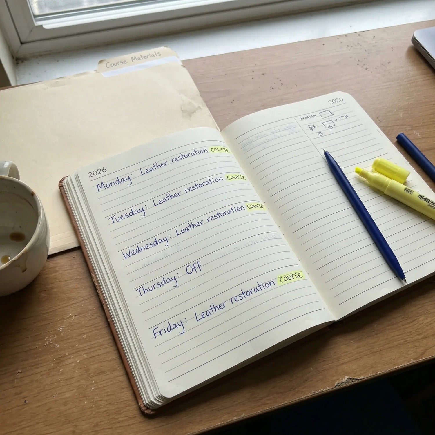 Open notebook with daily schedule on a wooden desk next to a cup and pens. Advanced leather restoration courses by Letech