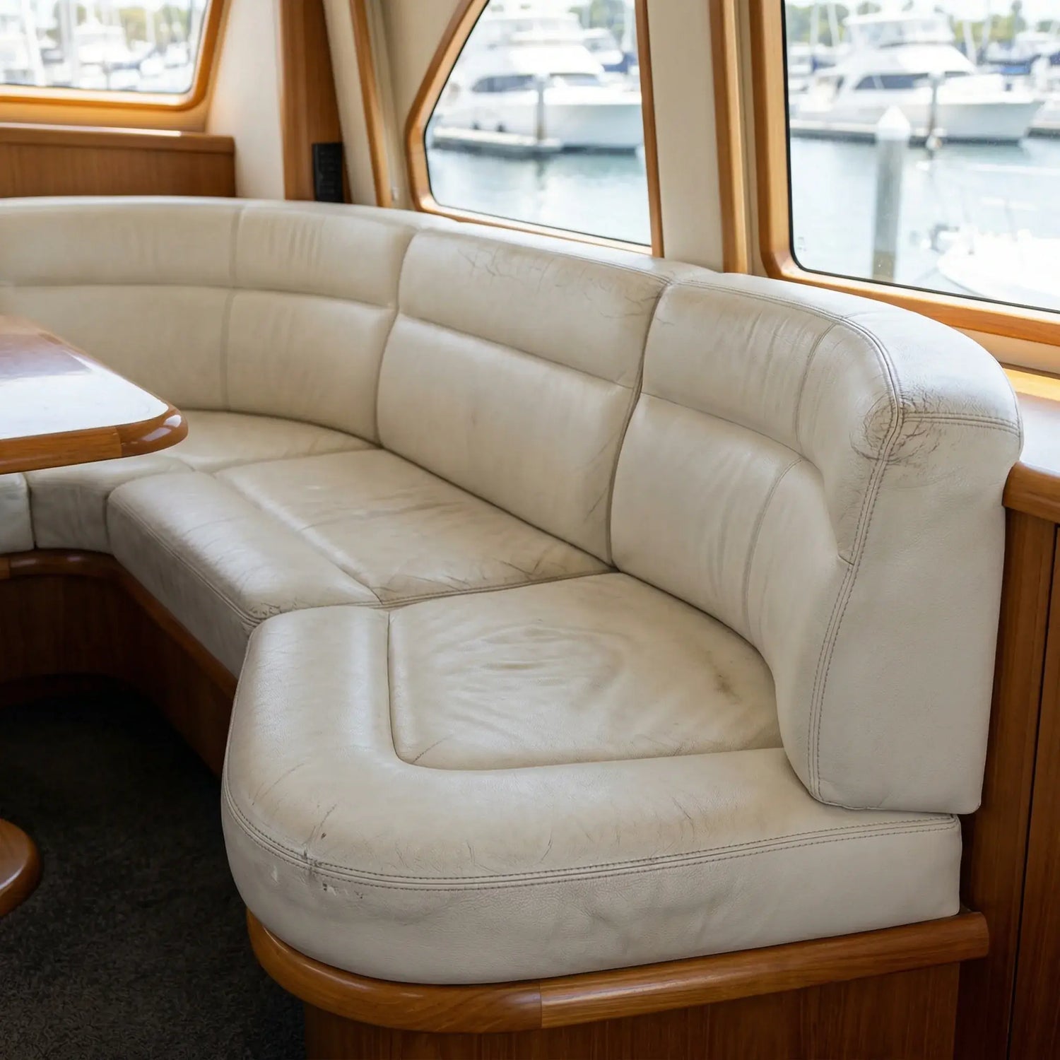 Beige leather sofa on a boat with windows showing water and boats. Boat leather repairs by LeTech