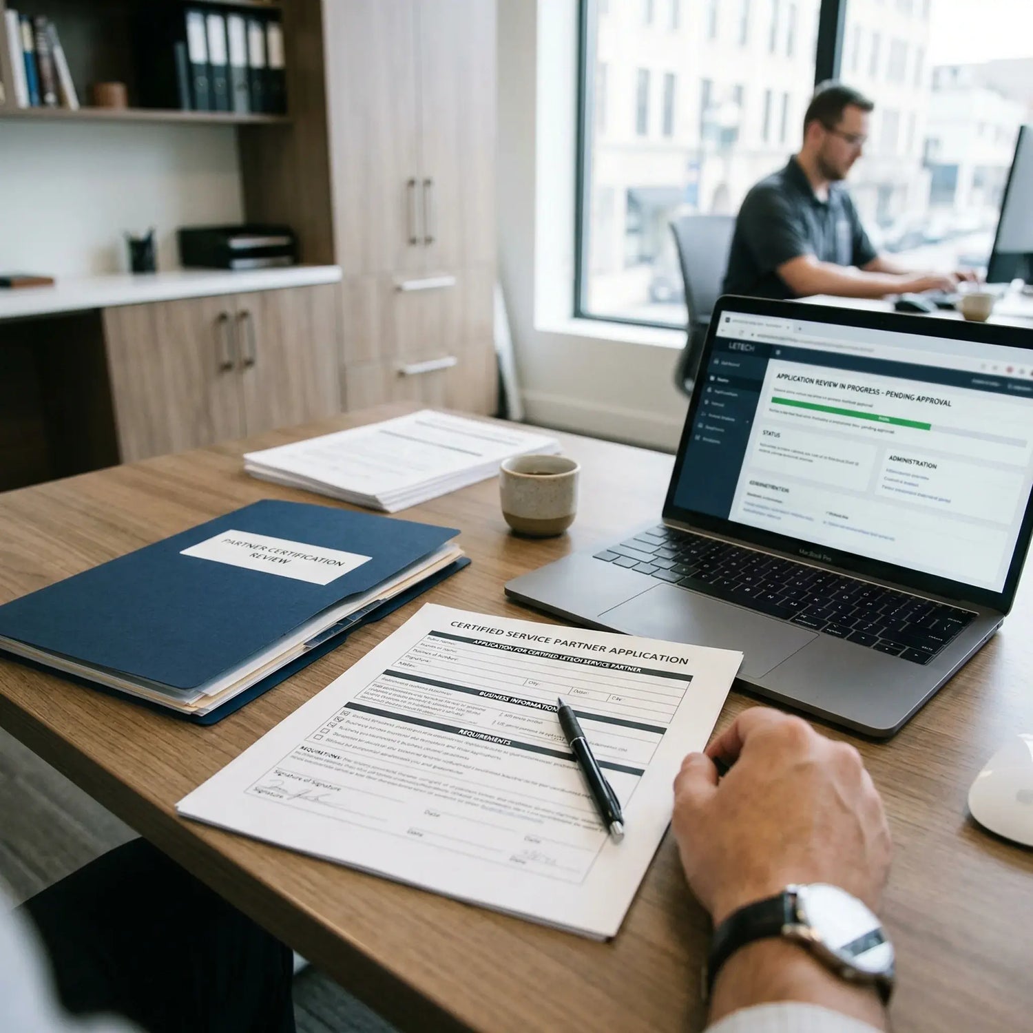 Person filling out a document at a desk with a laptop and notebook. Letech certified partner
